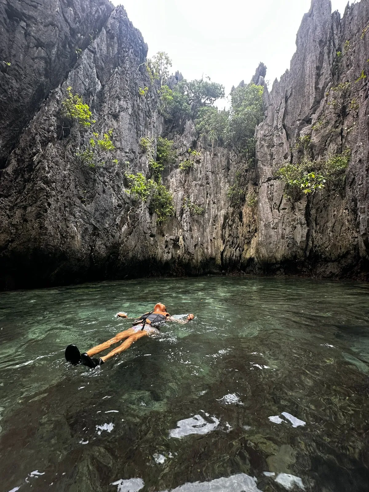 Ein friedlicher Moment beim Treiben im kristallklaren Wasser von El Nido, umgeben von hoch aufragenden Kalksteinfelsen und üppigem Grün.