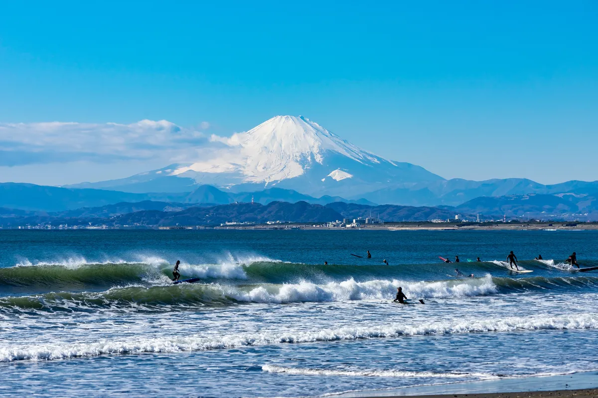 Blick auf den Berg Fuji vom Shonan Beach mit Meereswellen im Vordergrund
