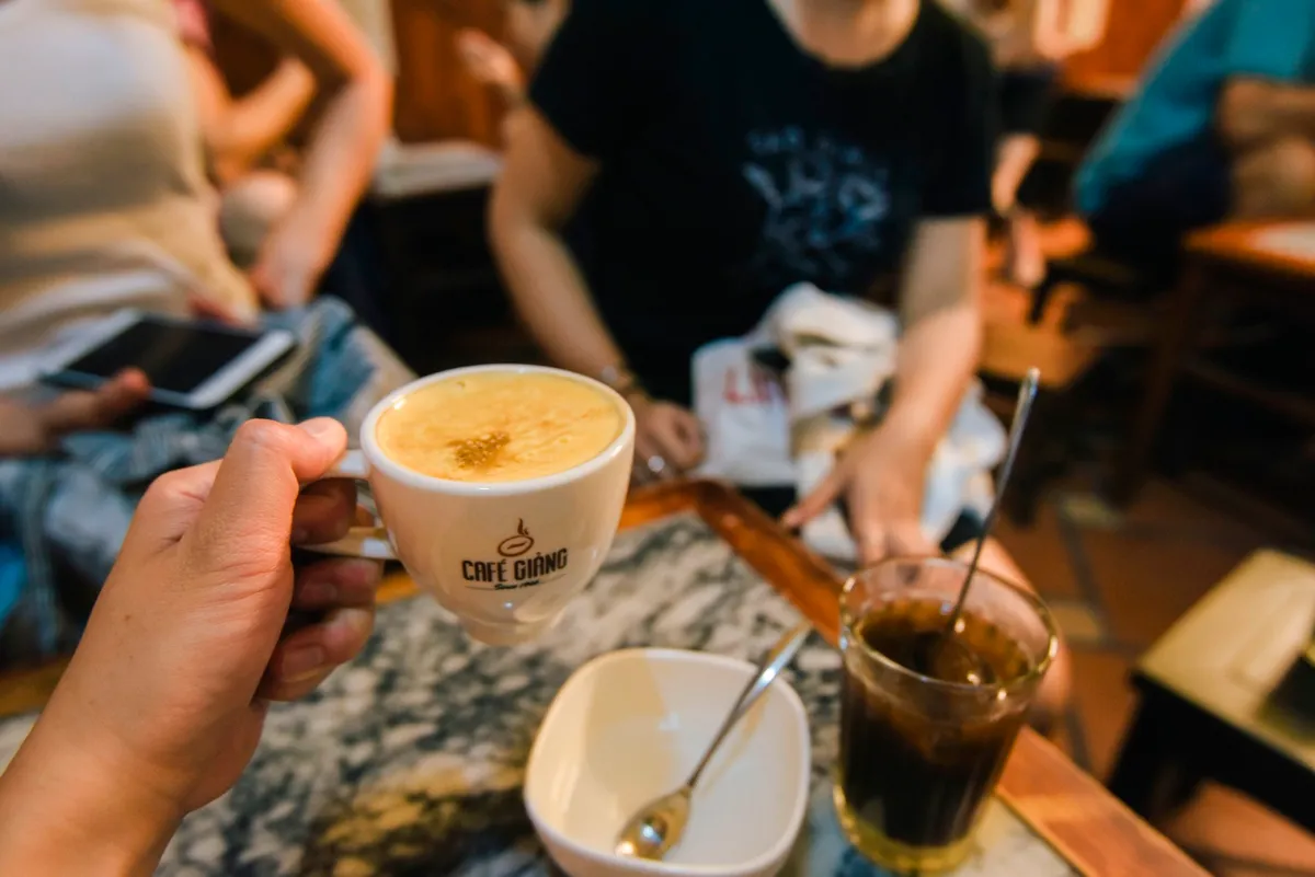 Le café à l'œuf est préparé en fouettant ensemble des jaunes d'œufs, du sucre blanc, du beurre et du lait concentré sucré jusqu'à obtenir un mélange crémeux et mousseux